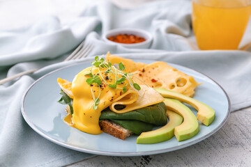 Tasty sandwich with florentine egg, cheese, avocado and juice on light background, closeup