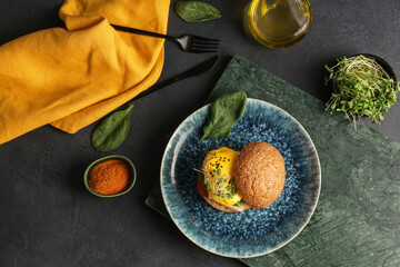 Plate with tasty burger and florentine egg on dark background
