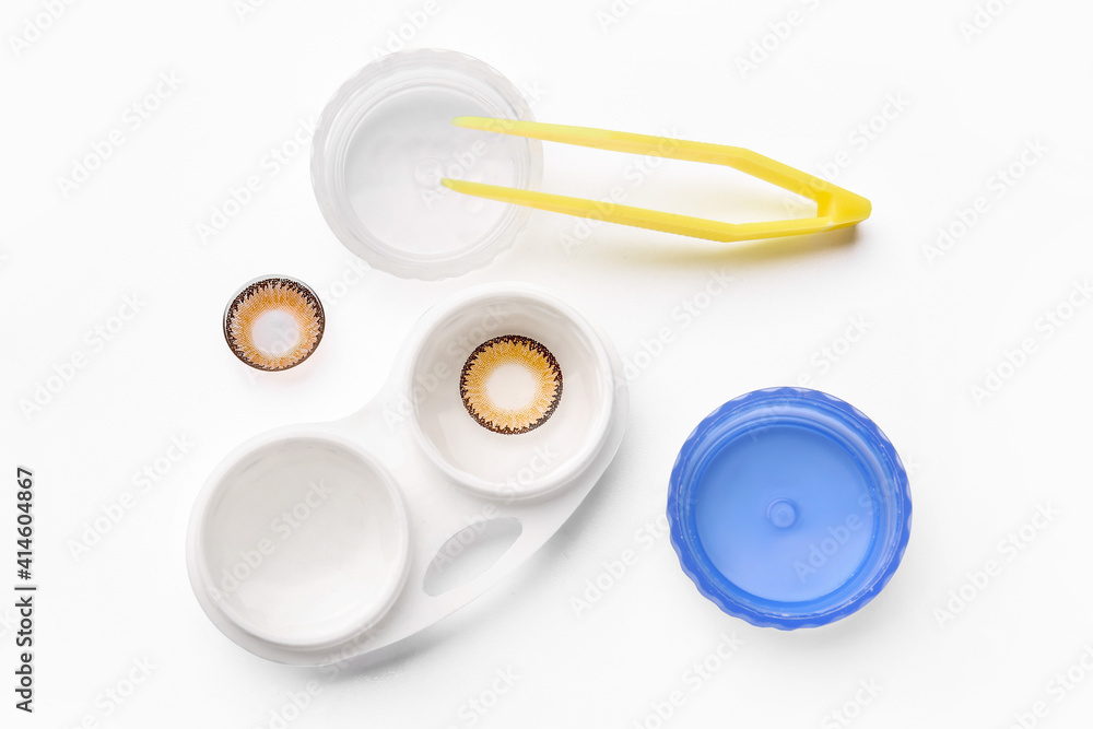 Sticker tweezers, color contact lenses and container on white background