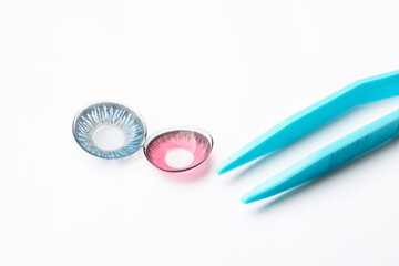 Tweezers with color contact lenses on white background
