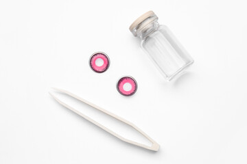 Tweezers, color contact lenses and bottle on white background