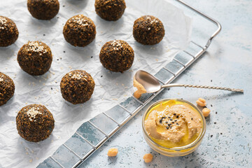 Tasty falafel balls and sauce on light background