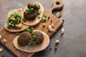 Fototapeta na wymiar Board with tasty falafel balls and pita on grunge background