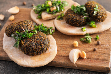 Board with tasty falafel balls and pita on grunge background
