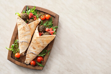 Board with tasty falafel pita on light background