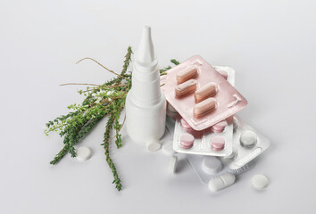 Bottle with drops, blooming plant and pills on white background