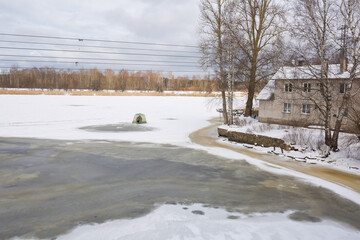 Frozen lake in winter with many snow and house.