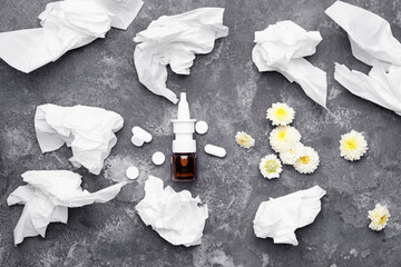 Bottle of drops, flowers and used tissues on dark background