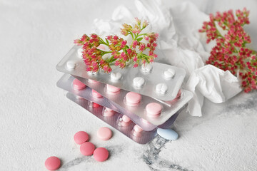 Pills, flowers and used tissue on light background