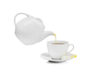 Pouring of hot tea from teapot into cup on white background