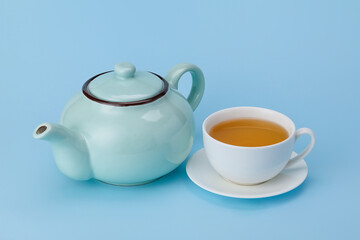 Stylish teapot and cup of tea on color background