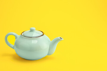 Stylish teapot on color background