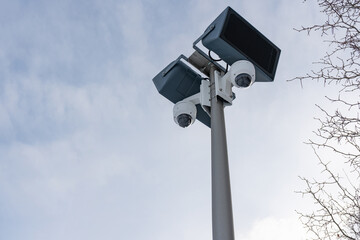 CCTV cameras and loudspeakers on the background of the sky and tree branches with thorns