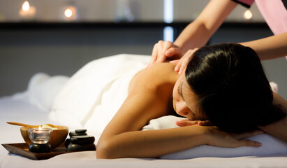 Obraz na płótnie Canvas Asian women masseuse hand to massage services to woman customers sleep look a relax with dress white robe in. Massage equipment wooden bowl on wood plates with candle light put near a woman customer