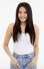 Portrait of One Asian adult woman with long black hair standing, smiling and looking at a camera with hands in blue jean. Woman wear a white camisole and jeans shoot with white background in a Studio