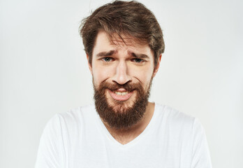 Obraz premium Bearded man in a white T-shirt on a light background sad face emotions beard
