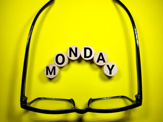 Selective focus.Glasses and cylinder block with word MONDAY on yellow background.Shot were noise...