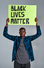 Confident young african american guy in casual clothes looking at camera, holding demonstration...