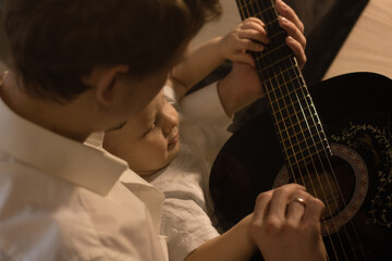 Dad and son play the guitar at home. Image contains noise and selective focus
