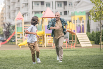 Dad and son running on the playground and feeling happy