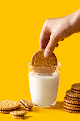 Breakfast concept. Hand dipping sandwich biscuits cookie filling with chocolate cream anto  a glass...