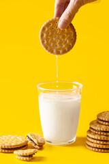 Breakfast concept. Hand dipping sandwich biscuits cookie filling with chocolate cream anto  a glass...