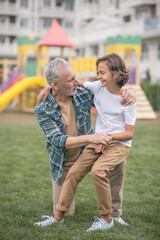 Gray-haired man hugging his son and looking happy