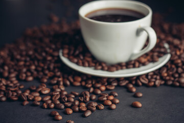 coffee beans sprinkled on a gray table and a cup saucer arabica drink