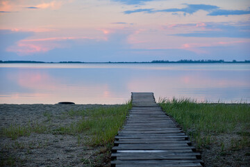 Obraz premium wooden path to the lake at sunset