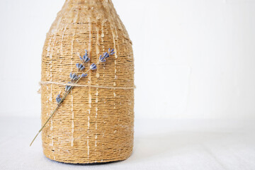 Wine bottle candlestick with melted paraffin and dry lavender flowers on white background.