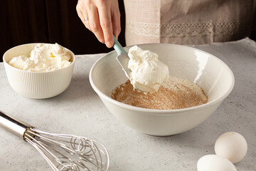 Woman adding cream cheese into the bowl. Home cooking