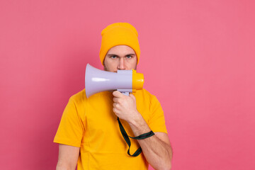 Serious european man with megaphone on pink background