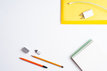 Desktop. Stationery and mobile phone charger on white background.