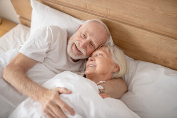 Aged couple lying in bed and looking relaxed