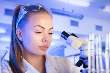 Laboratory concept background. Young scientist during experiment and using microscope in modern laboratory.
