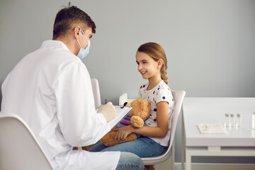 Male doctor talks to the little girl and does a regular medical examination, writing everything...