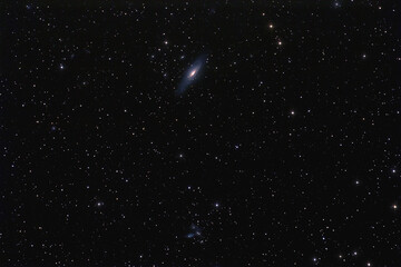 NGC 7331 galaxy and cluster of galaxies photographed with long exposure through a telescope.