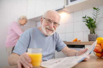 Senior grey-haired man sitting at the table in the kitchen