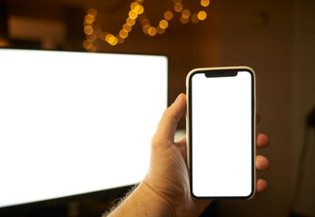 Photo of the white blank screen of the computer and hand holding cellphone. Digital web space concept