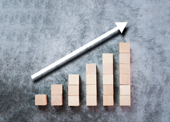 Wooden block stacking as ladder, step stairs with white arrow up on gray background, Concept of success in business growth, copy space