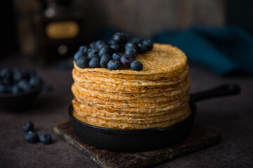 Homemade thin pancakes in a frying pan with blueberries, maslenitsa