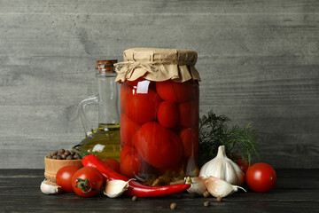 Pickled tomatoes and ingredients against gray background