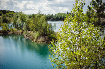 Lake on the background of rocks and fir trees. Canyon. The nature of spring, summer. Place for text and design. Landscape of an old flooded industrial granite quarry filled with water.