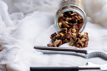 walnut kernels scattered from the jar lie on a napkin next to the nutcracker