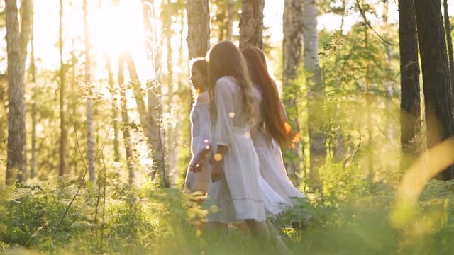 Girls walk through the woods dressed in white dresses