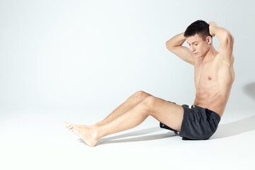 Fototapeta na wymiar bodybuilder in shorts doing fitness in a bright room inflated torso