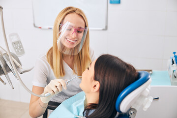 Fototapeta premium Positive delighted stomatologist treating her cute patient