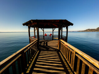 Pleasant  view of the coast of Lake Garda. Lonely Sailboat in the middle of the lake on a Sunny day.