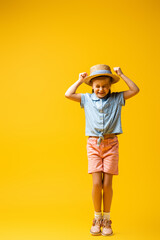 full length of excited kid with clenched fists on yellow