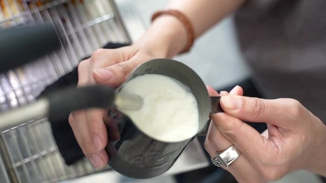 Barista steaming milk to pour latte art in coffee cups at cafe footage video 4k 